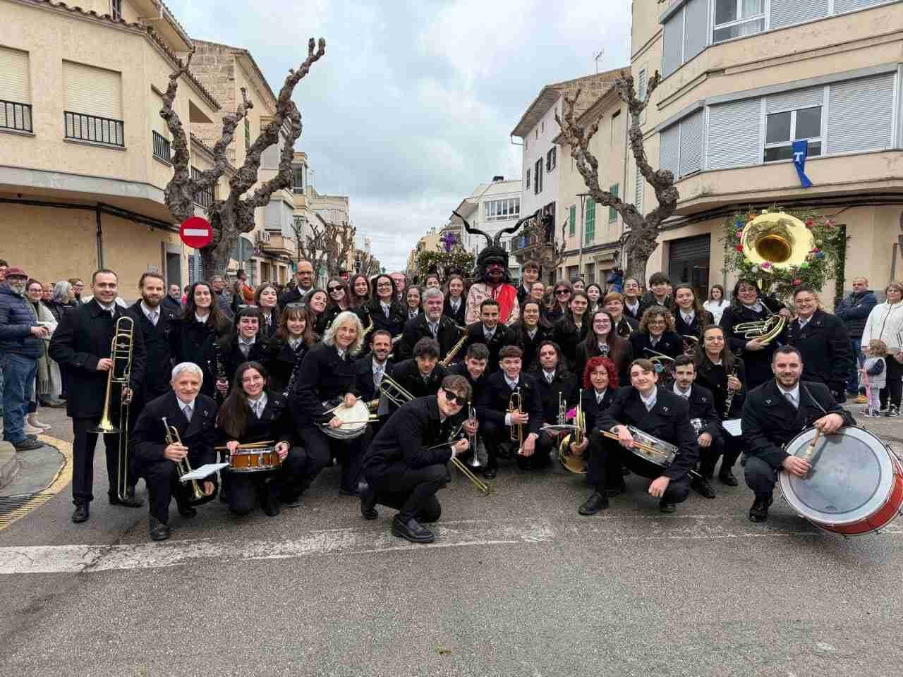 Gran grupo de músicos de la Banda de Música de Manacor posando con sus instrumentos en la calle
