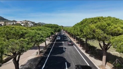 Fotografía aérea de una carretera en Son Servera con asfalto nuevo, señalización blanca impecable y rodeada de pinos
