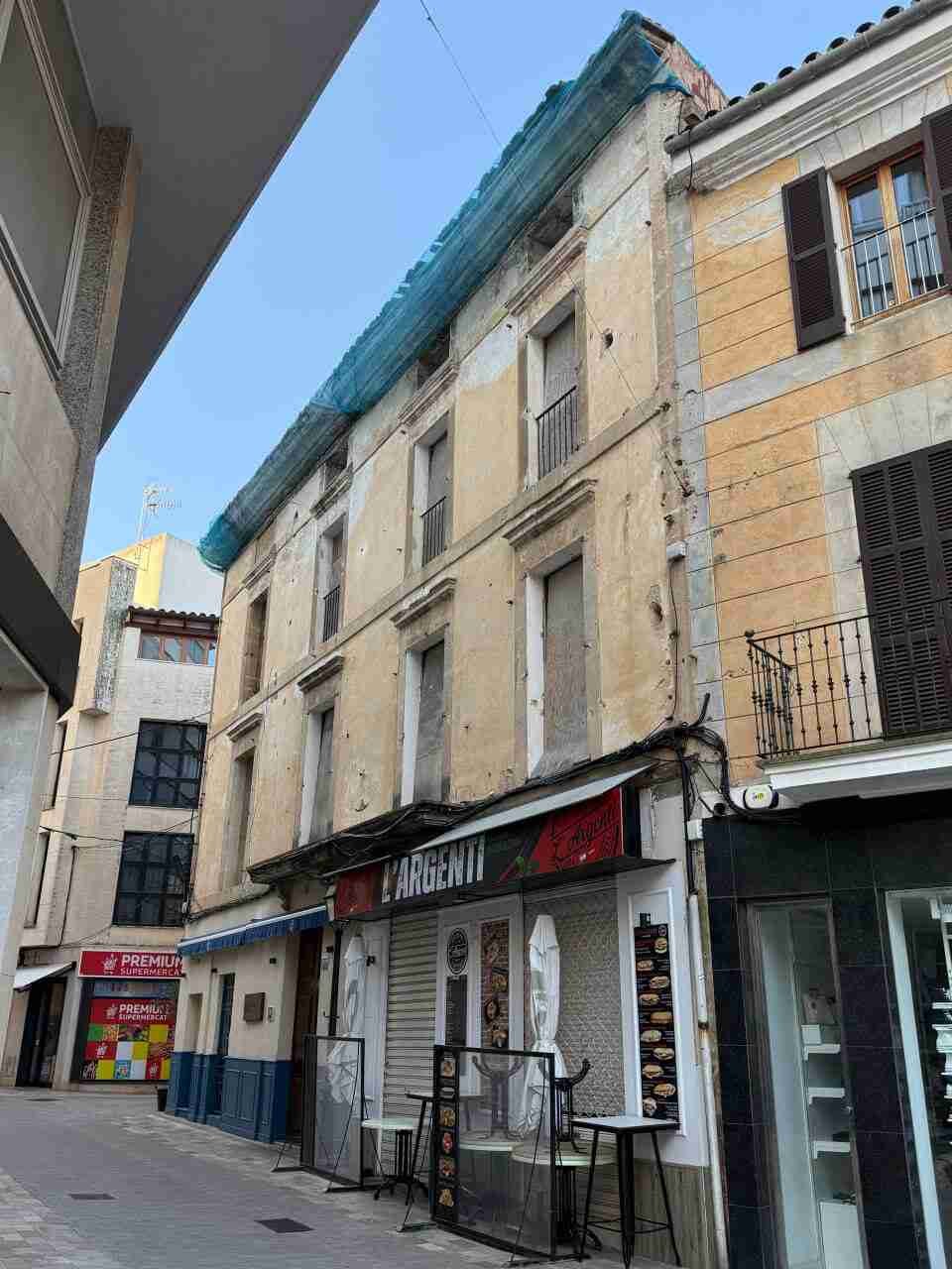 Fachada de un edificio antiguo en Manacor con redes de seguridad en la parte superior y un establecimiento cerrado en la planta baja