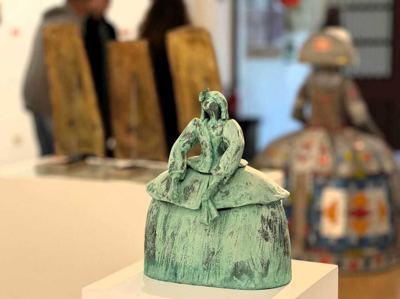 Detalle de una pequeña escultura contemporánea de una Menina con acabado en color verde oxidado, expuesta en el centro de arte de Inca