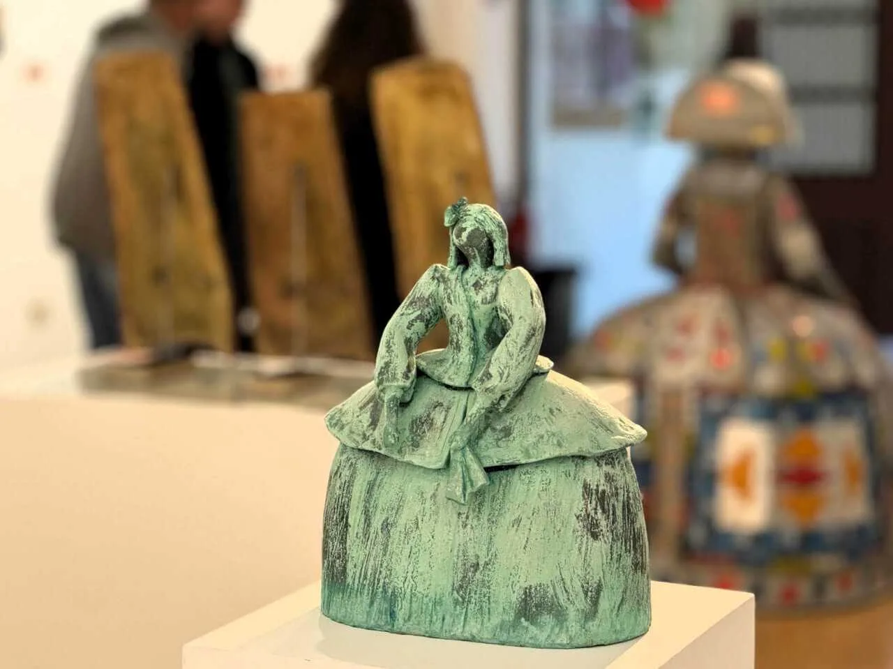 Detalle de una pequeña escultura contemporánea de una Menina con acabado en color verde oxidado, expuesta en el centro de arte de Inca
