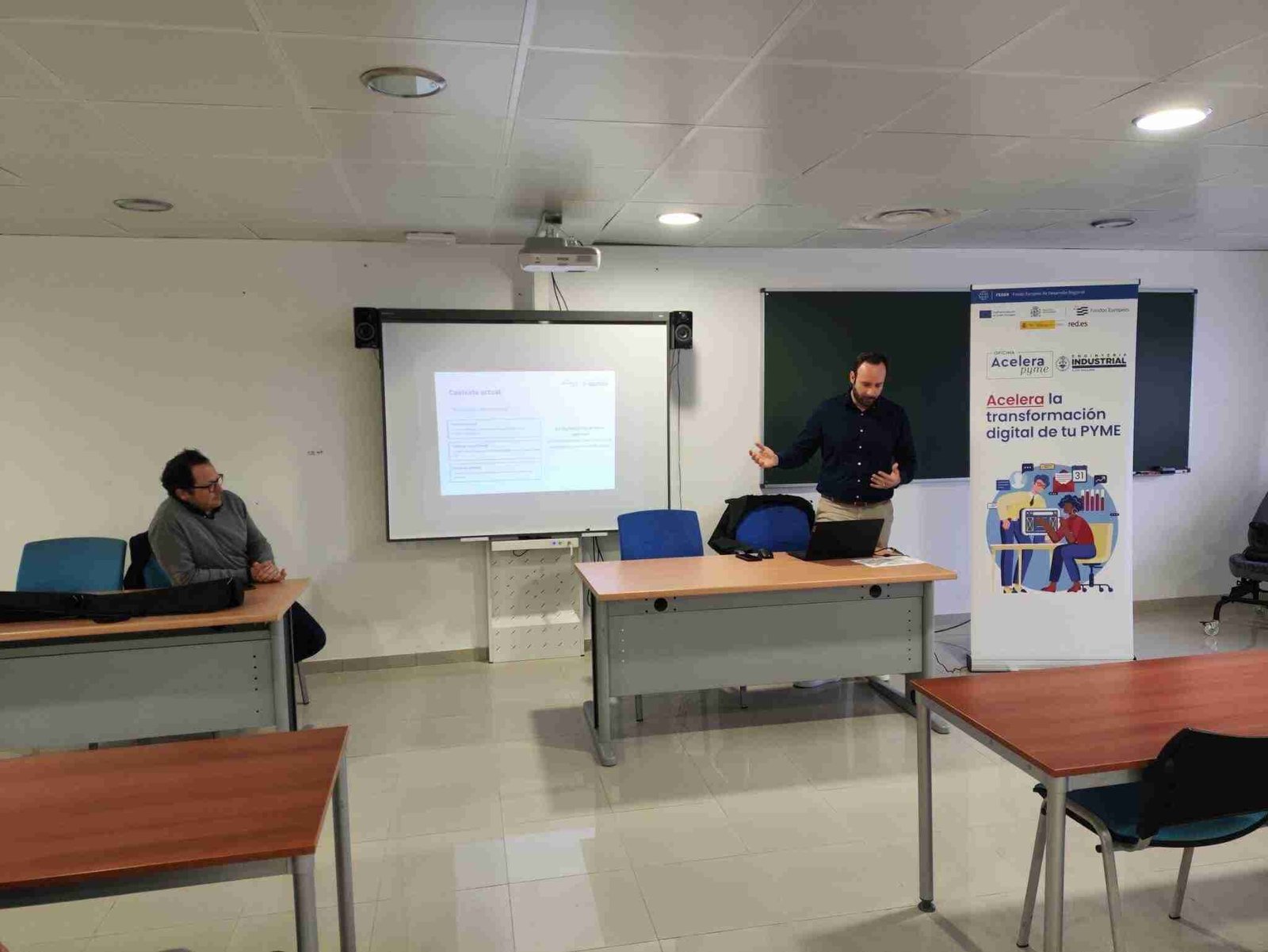 Un ponente explica recursos tecnológicos ante un cartel de Acelera Pyme en Son Servera