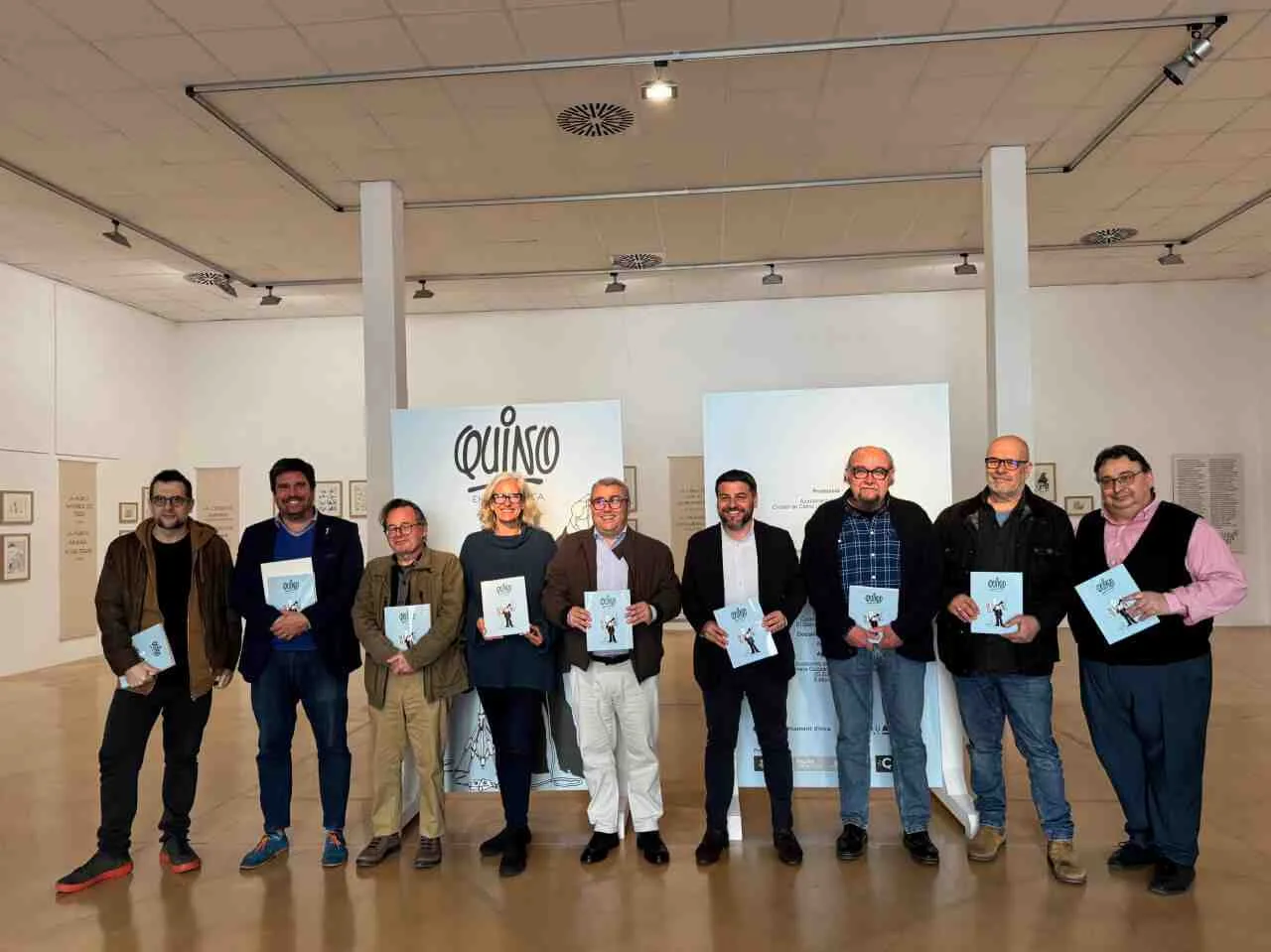 Grupo de representantes culturales y autoridades posando con el catálogo de la exposición «Quino en la música» en Sa Quartera de Inca
