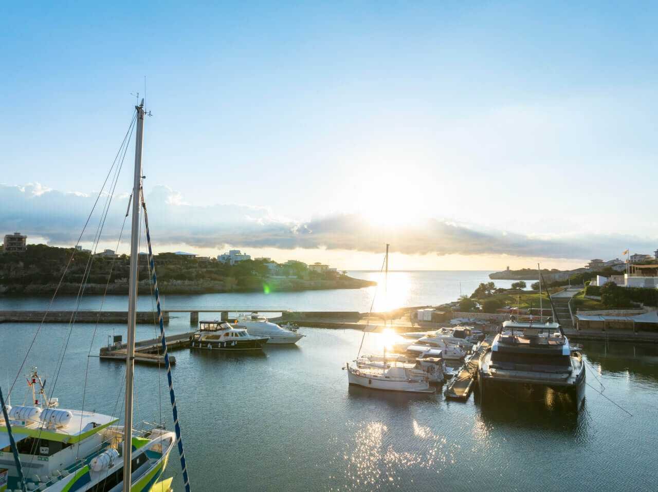 Vista panorámica de los amarres en el puerto de Porto Cristo con el sol en el horizonte