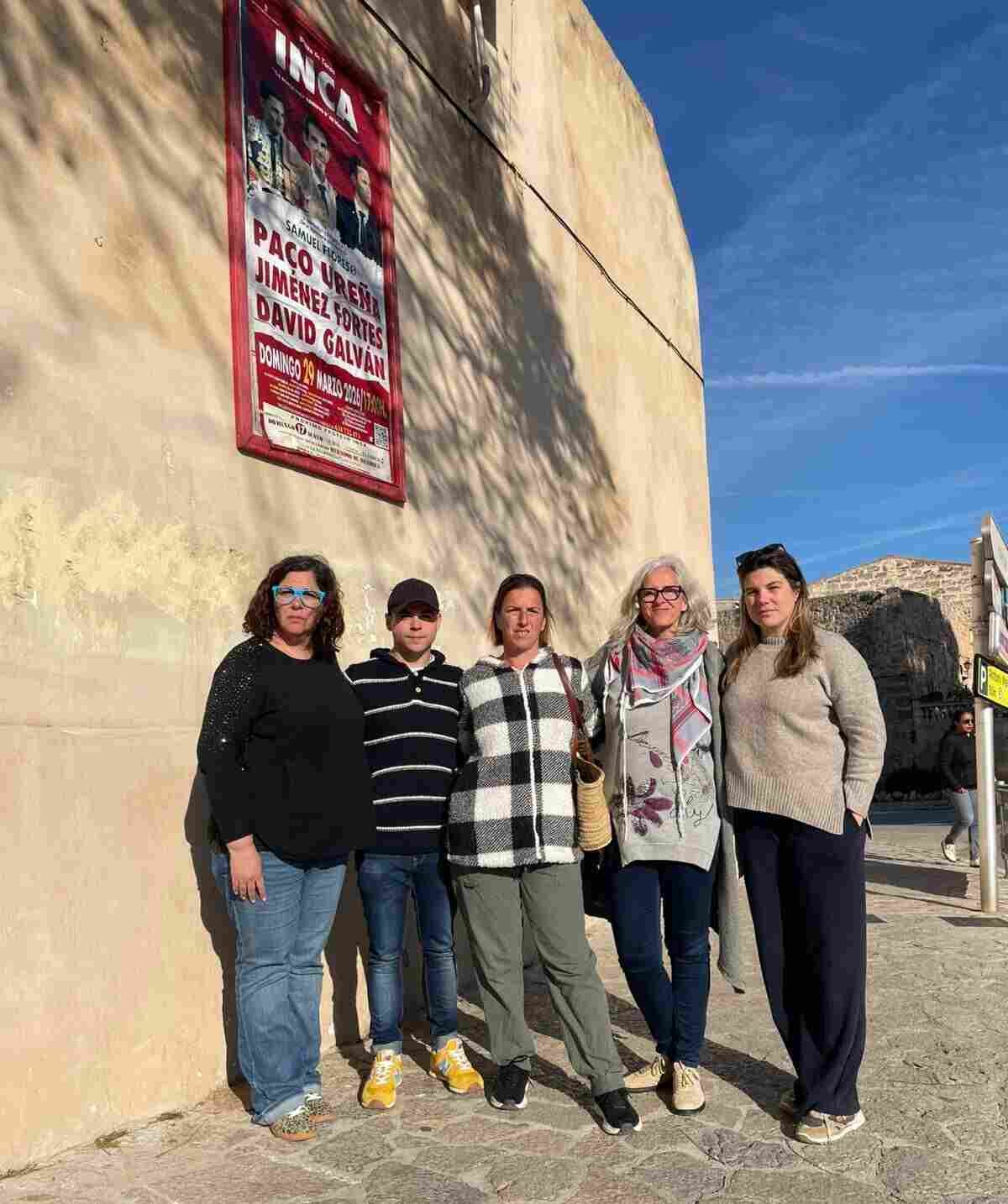 Integrantes de la formación separatista MÉS per Inca posan junto al cartel de la corrida de toros de mañana domingo en la plaza de Inca para denunciar el acceso de menores