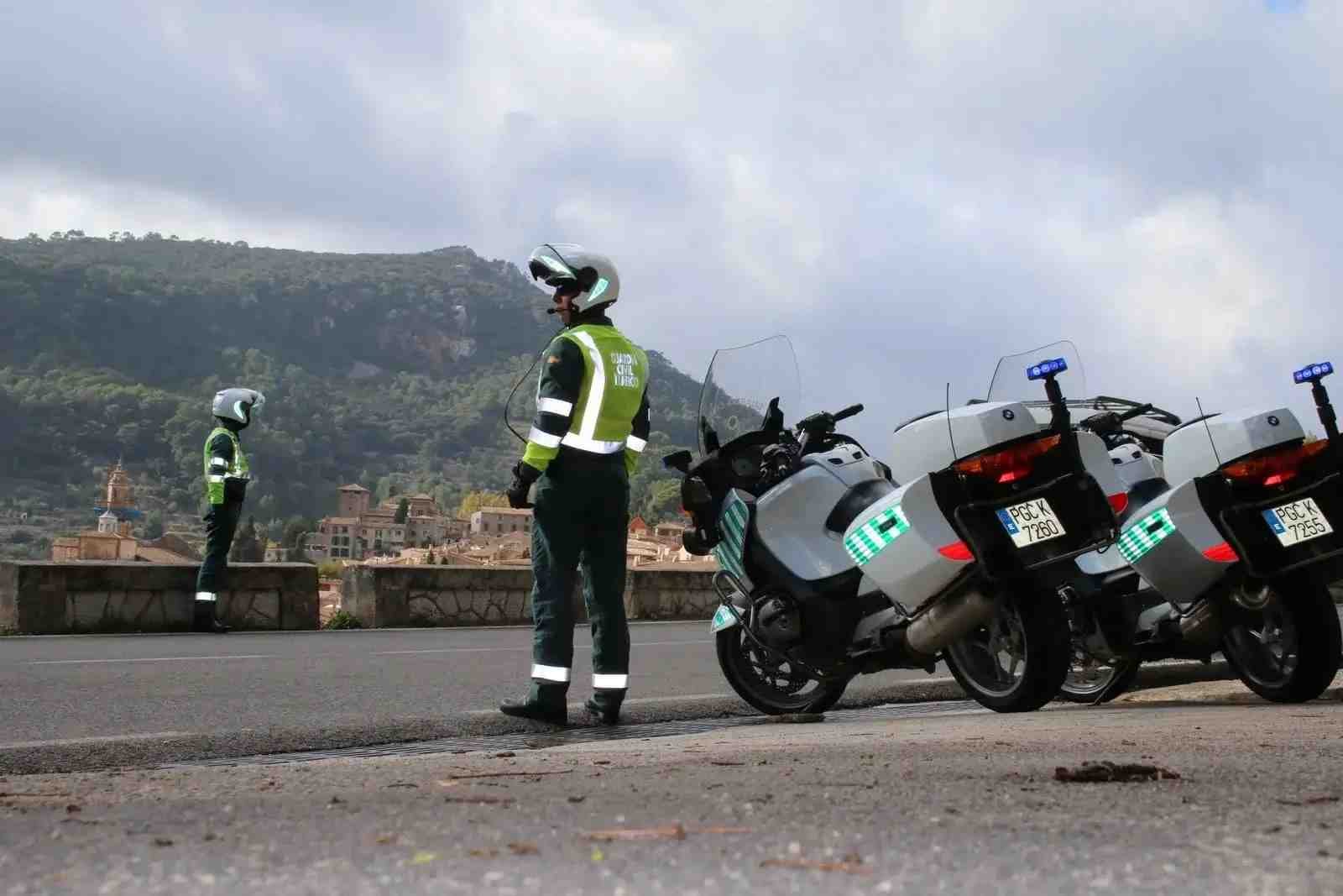 Dos agentes de la Guardia Civil de Tráfico junto a sus motos en una carretera