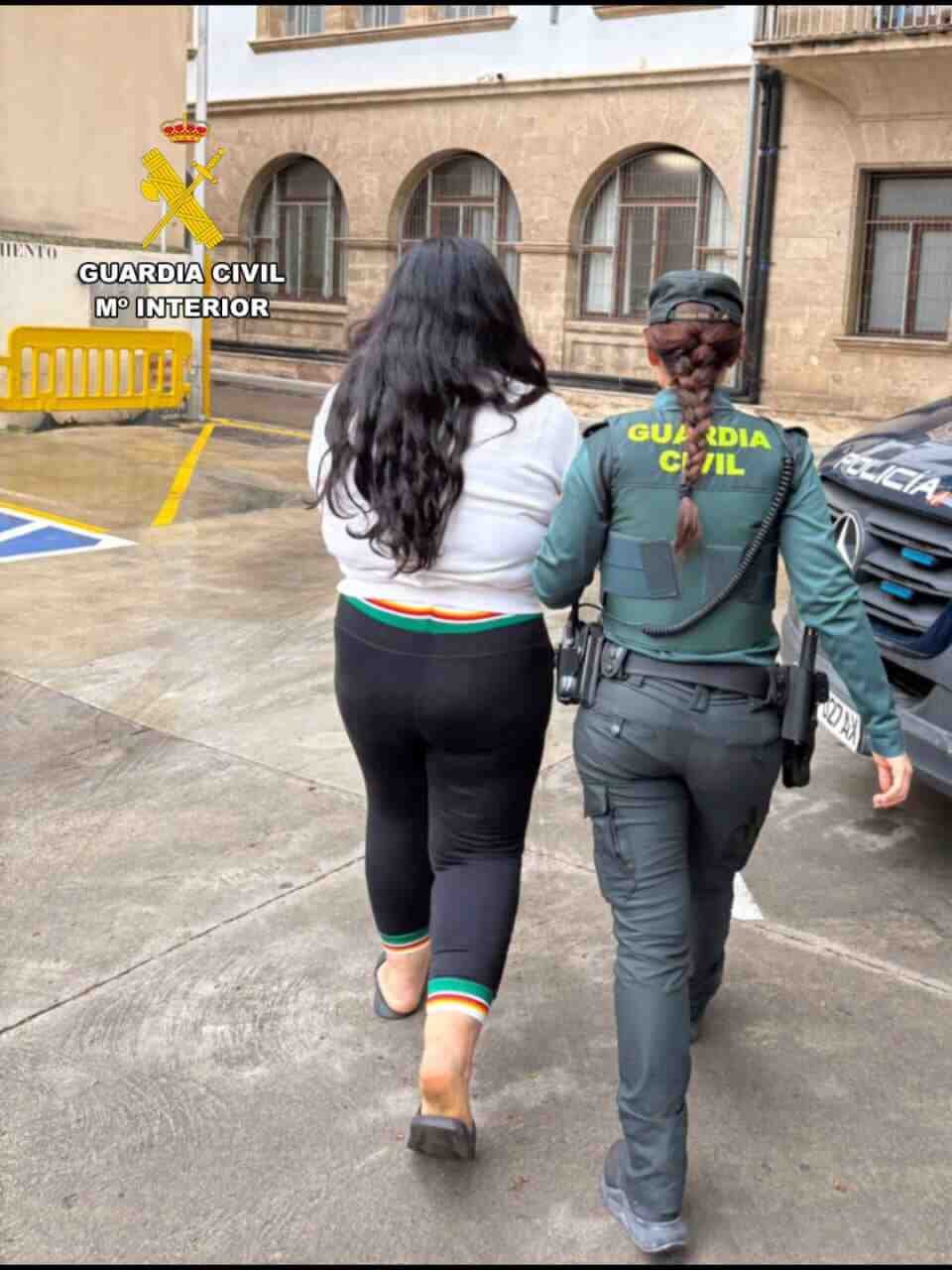 Una agente de la Guardia Civil escolta a una mujer magrebí detenida de espaldas hacia un vehículo oficial