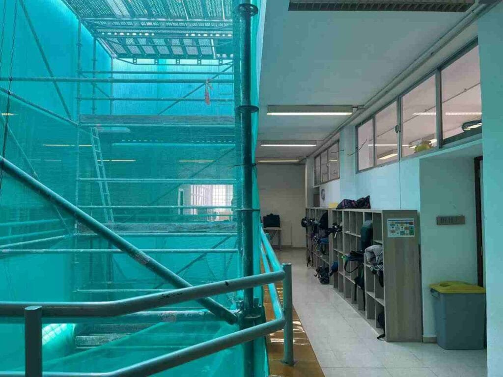 Estructura de andamios con red protectora bajo el hueco de la claraboya en el interior del colegio