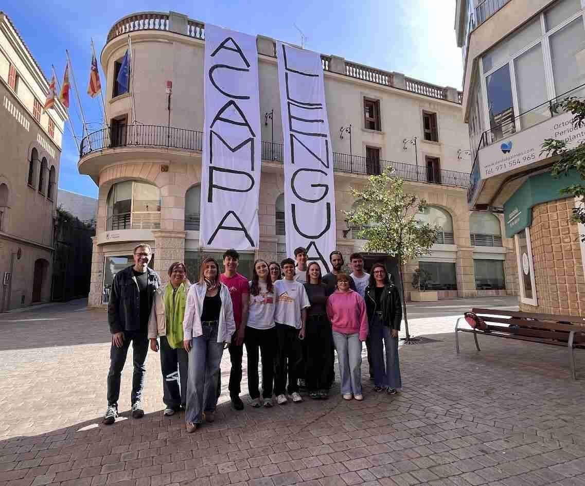 Dos grandes lonas blancas verticales con el texto ACAMPA LLENGUA cuelgan del balcón del Ayuntamiento de Manacor