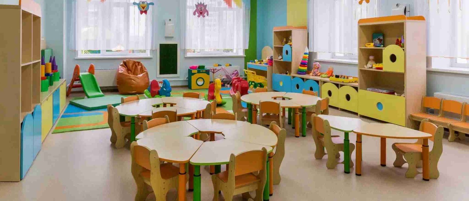 Aula de un centro de educación infantil con mesas amarillas y material pedagógico