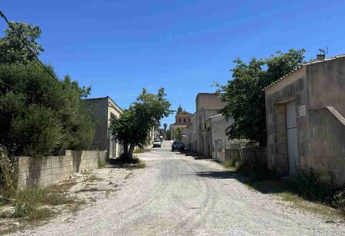 Vista de una calle de tierra y piedras en mal estado en el núcleo de Cas Concos en el municipio de Felanitx