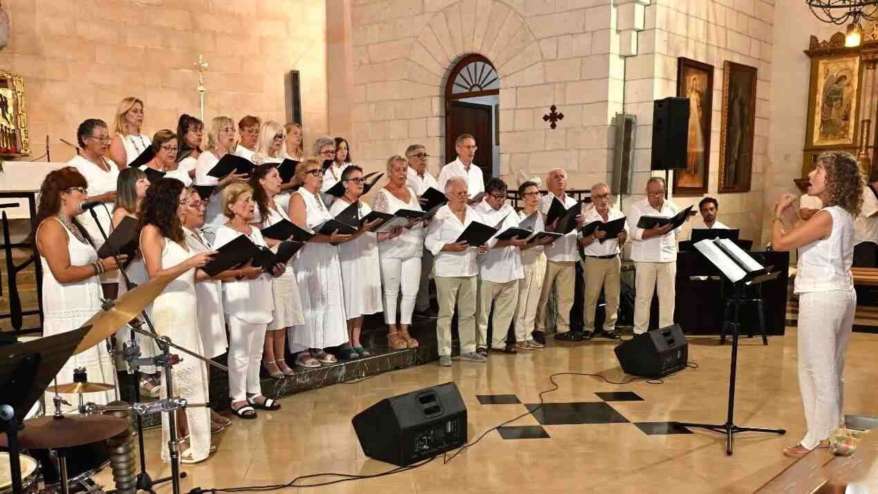 Los miembros de la Coral de Adultos del Conservatorio de Manacor cantan con vestimenta blanca en el interior de la iglesia