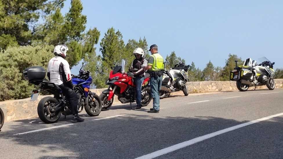 Agente de la Guardia Civil de Tráfico inspeccionando a varios motoristas en una carretera de Mallorca