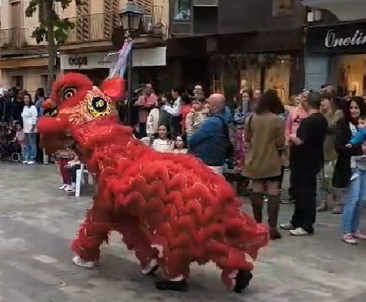 Un dragón chino rojo durante el pasacalle del Manacor Encantat en una calle peatonal de Manacor