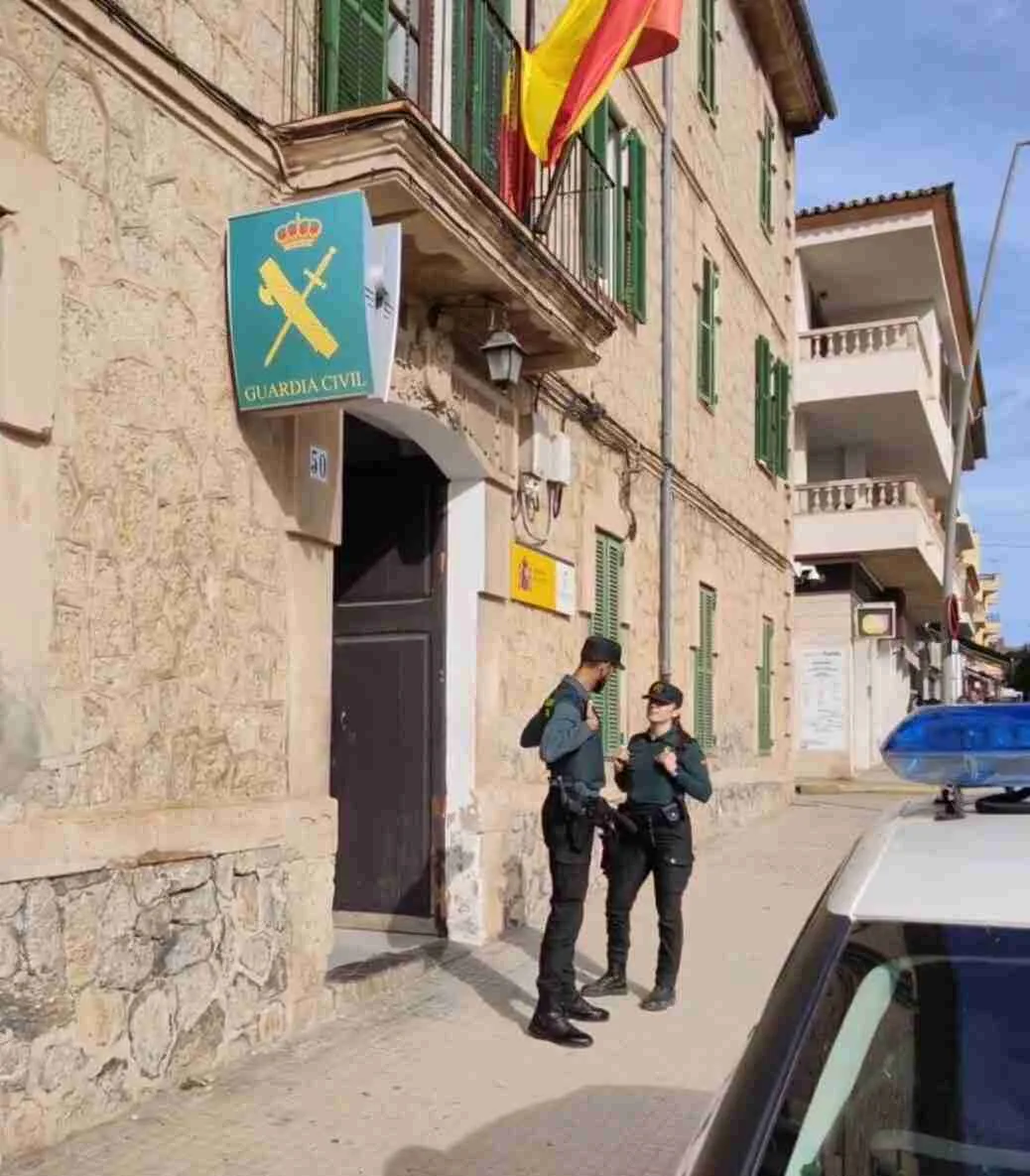 Dos agentes de la Guardia Civil conversando en la entrada del cuartel con un coche patrulla en primer término