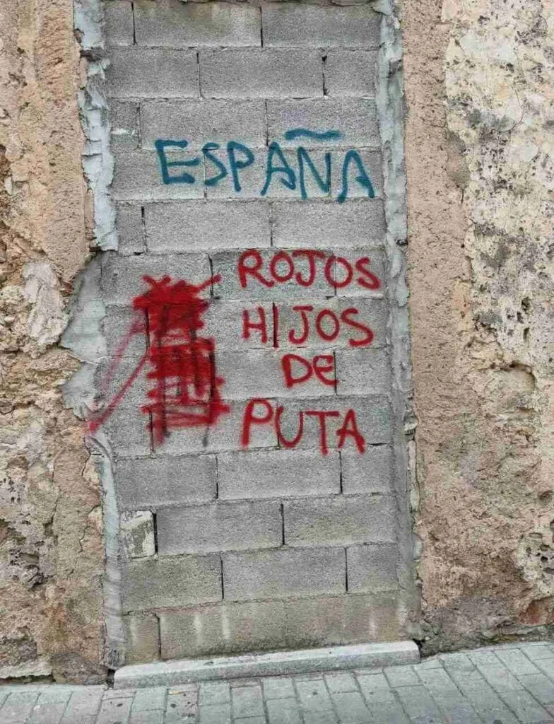 Vista completa de la pared vandalizada con las palabras "España" y "Rojos hijos de puta"