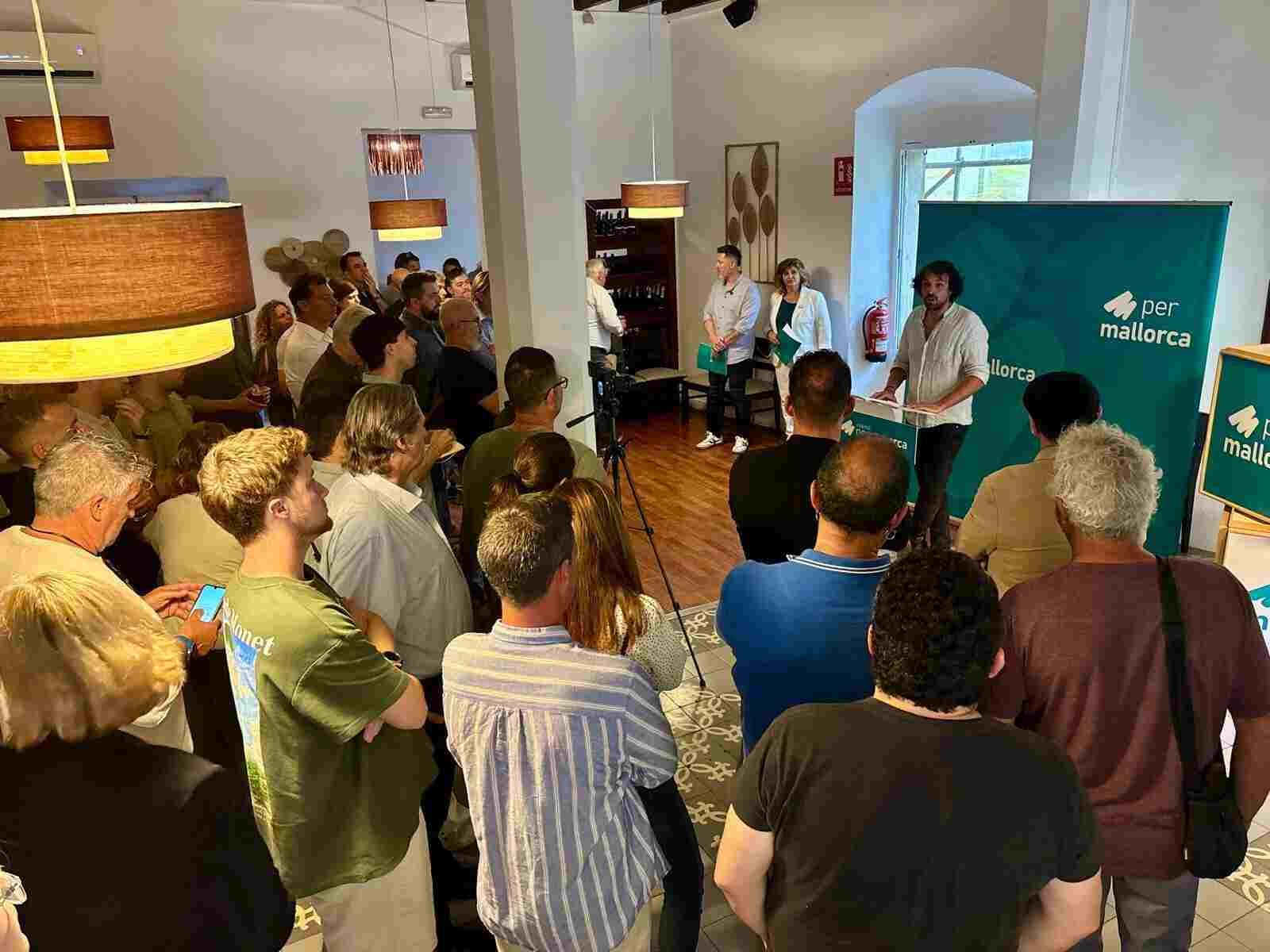 Asistentes de pie en el interior del restaurante Mig i Mig escuchando la presentación de Coalició per Mallorca