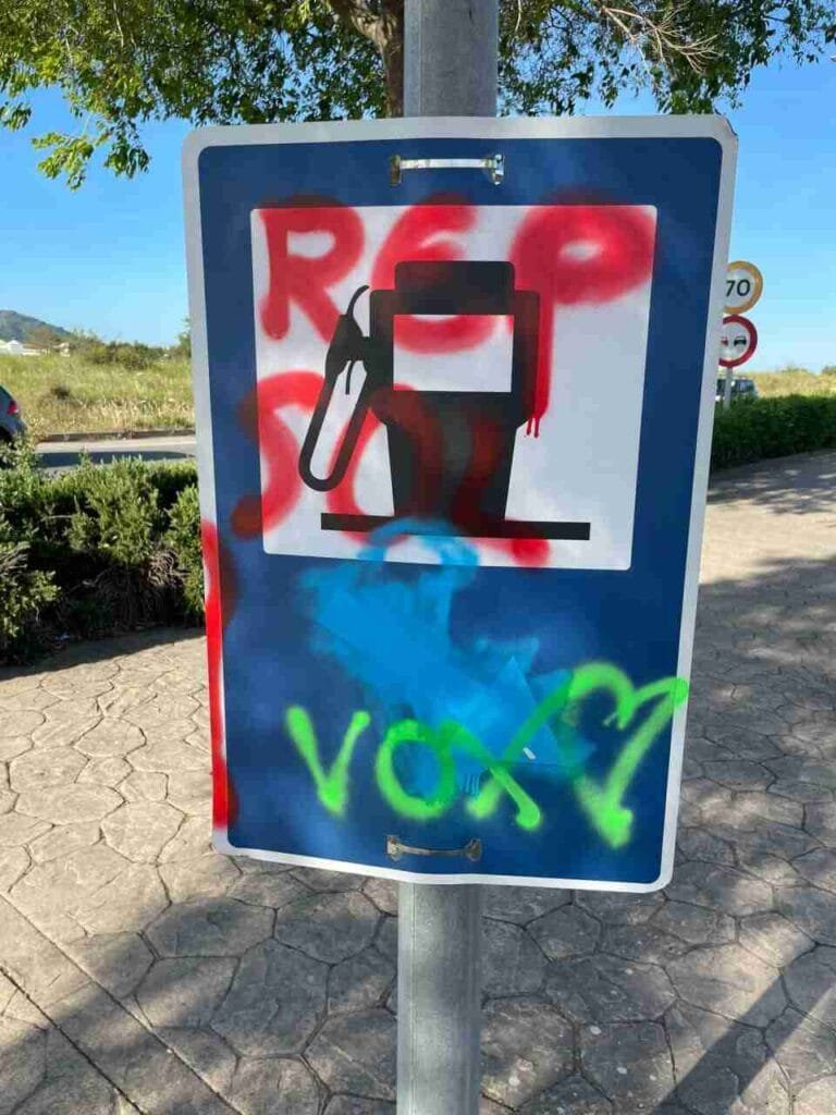 Señal de servicio de gasolinera emborronada con pintura y el nombre de Vox escrito en verde