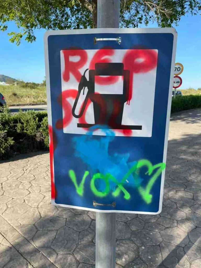 Señal de servicio de gasolinera emborronada con pintura y el nombre de Vox escrito en verde