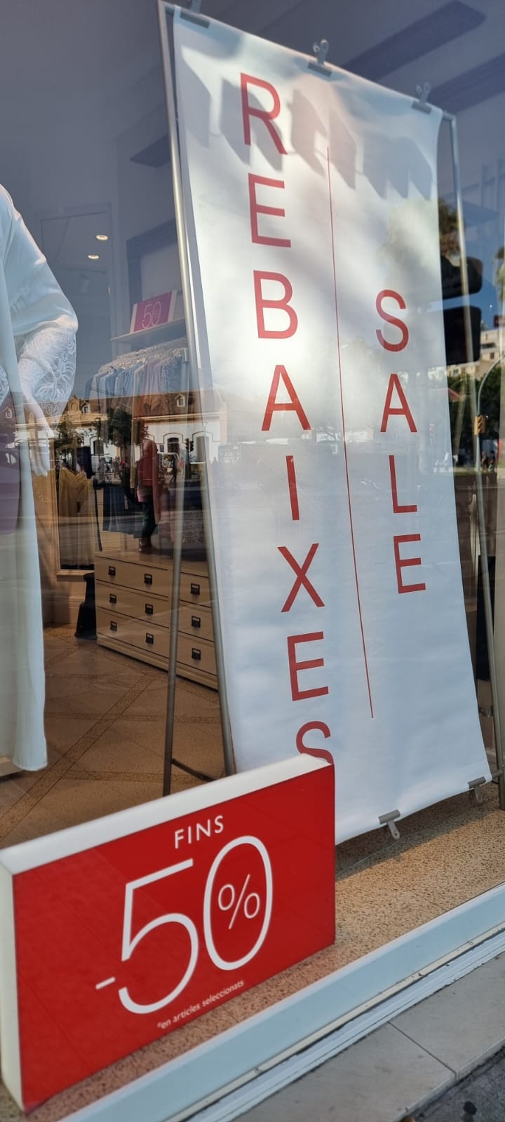 Escaparate de una tienda de ropa con carteles rojos donde se lee la palabra Rebajas en varios idiomas