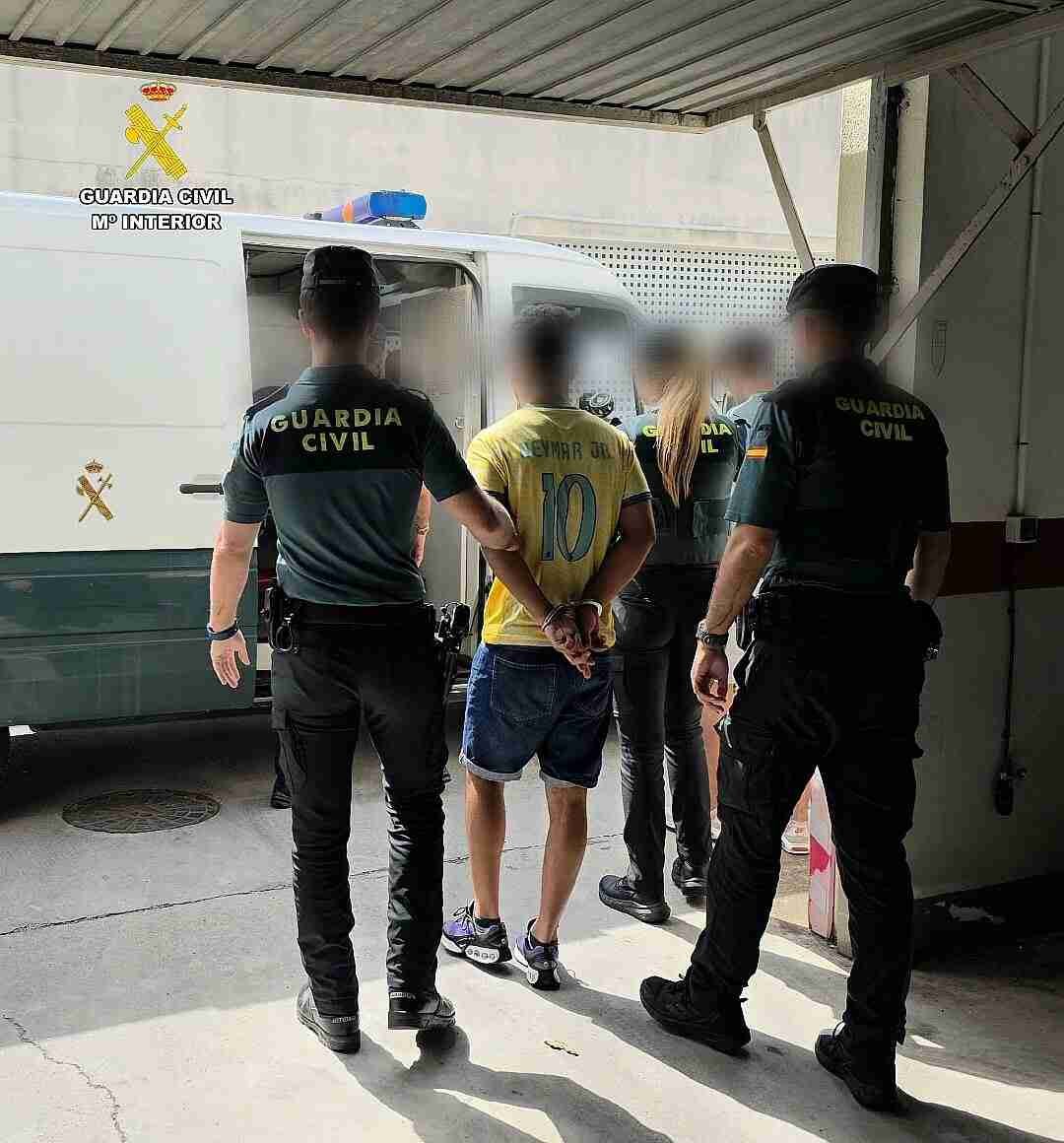 Agentes de la Guardia Civil custodian a un okupa magrebí detenido esposado hacia el furgón oficial