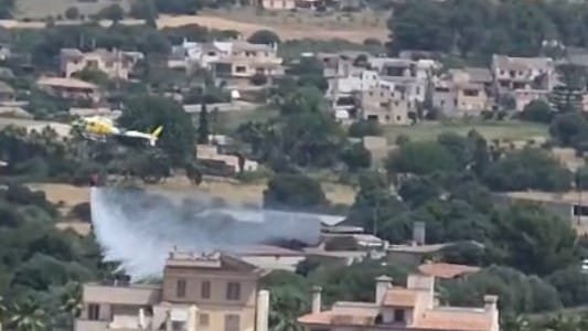 Helicóptero de los bomberos efectuando descargas de agua sobre el incendio en la zona del Auditorio de Manacor