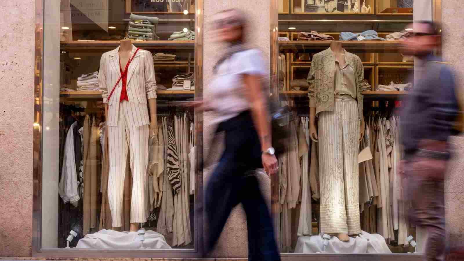 Una persona camina frente a un escaparate de una tienda de ropa