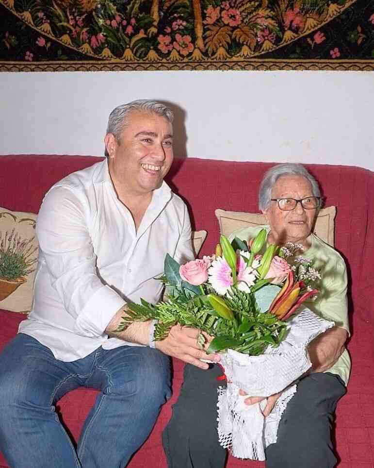 Francisca Ferrer Borràs sentada en el sofá recibiendo un ramo de flores por su 104 aniversario