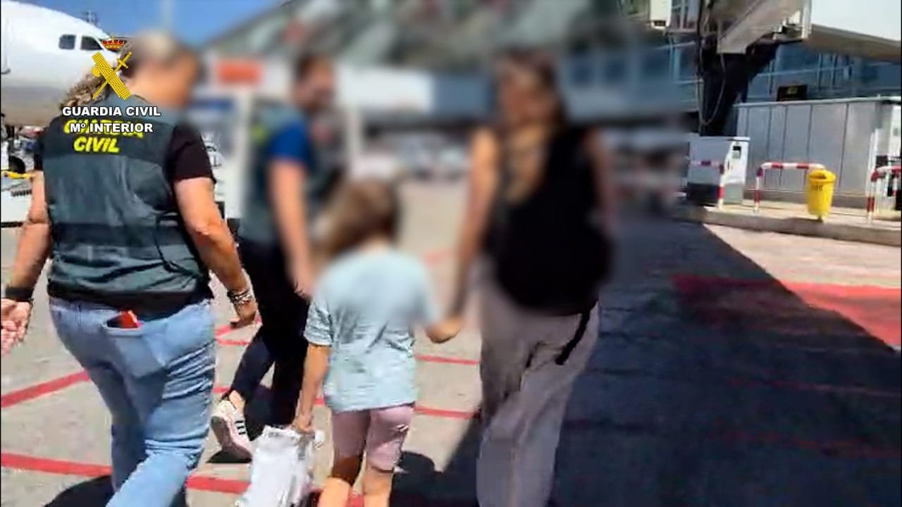 Agentes de la Guardia Civil escoltan a la menor de seis años rescatada por la pista de aterrizaje del aeropuerto de Mallorca