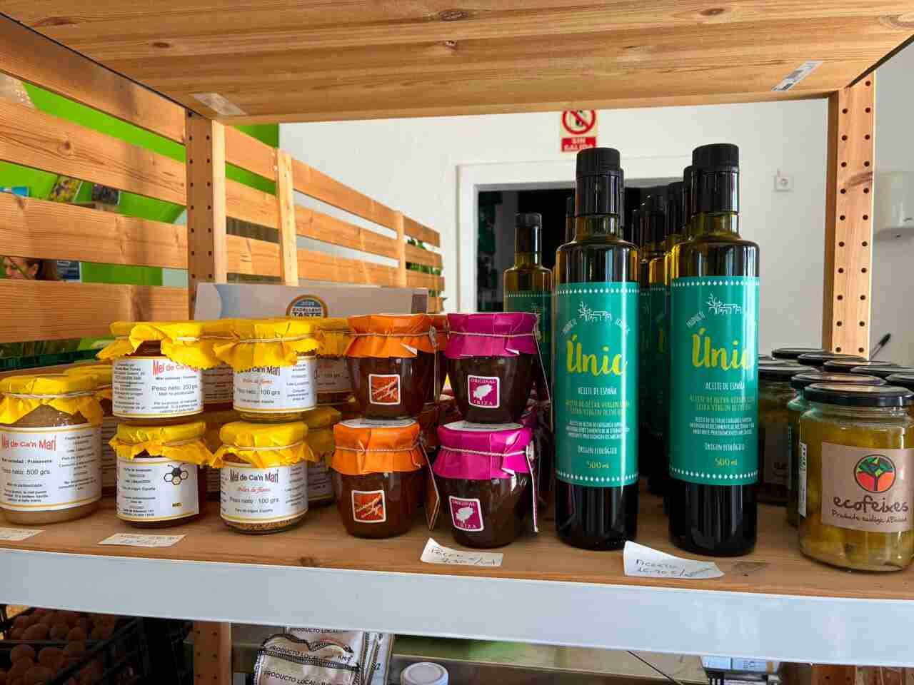 Estantería de madera con tarros de miel de Ca'n Marí y botellas de aceite de oliva Únic