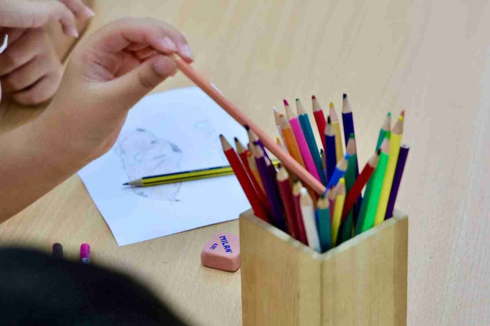 Niños en clase con lápices de colores listos para el próximo curso escolar