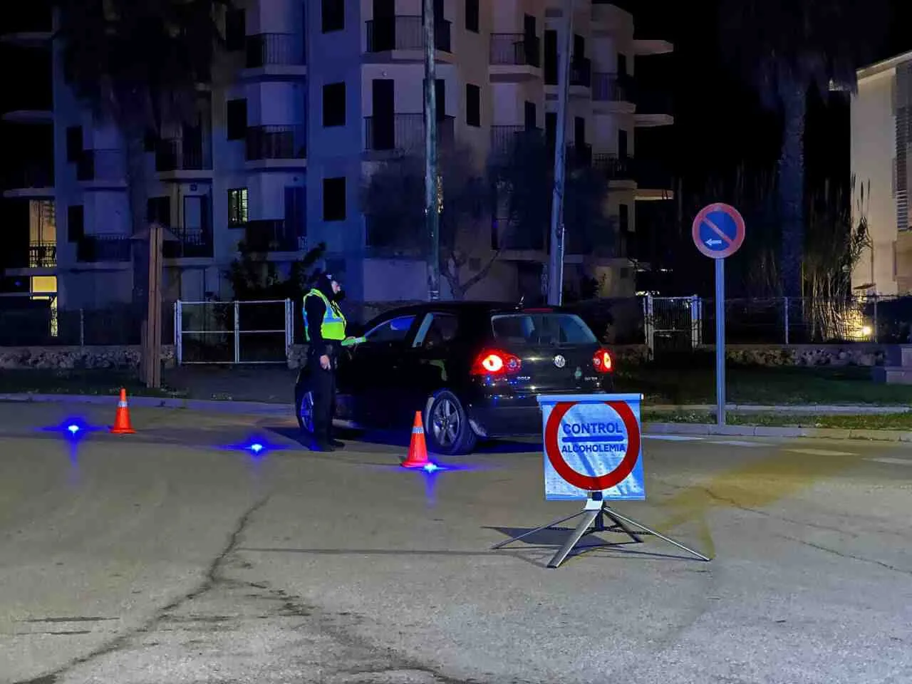Agente de la Policía Local de Felanitx inspeccionando un vehículo negro de noche junto a un cartel circular de control de alcoholemia