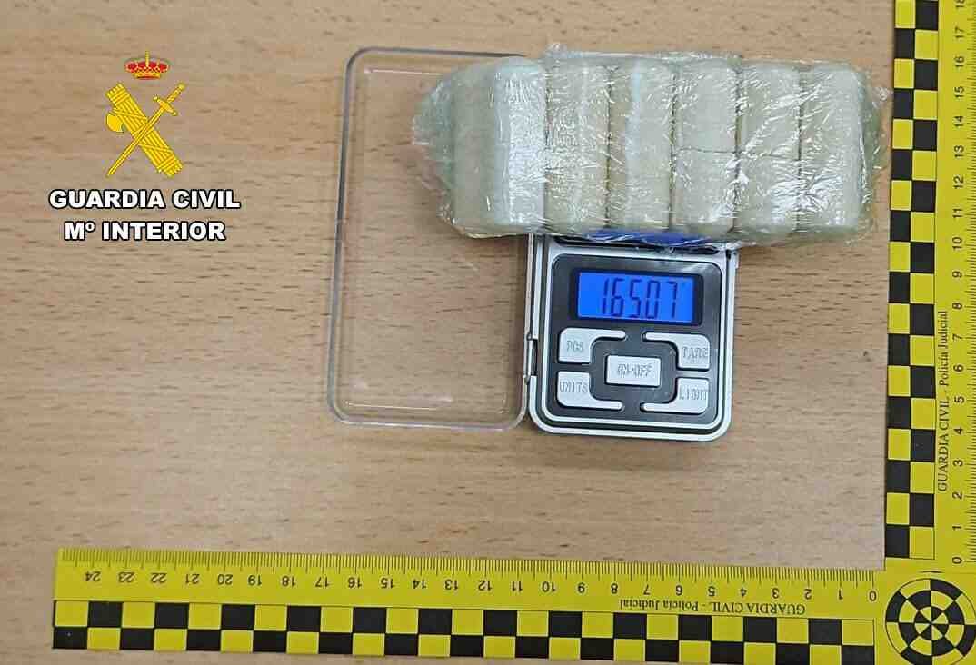 Un paquete plástico transparente con dosis de cocaína sobre una báscula digital de precisión que marca 165.07 gramos, junto al logotipo de la Guardia Civil