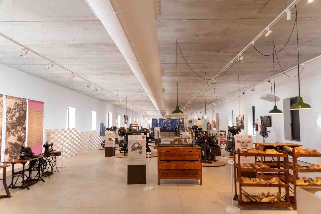 Sala de exposición del Museo del Calzado de Inca con maquinaria industrial de fabricación de calzado y estanterías con hormas de madera