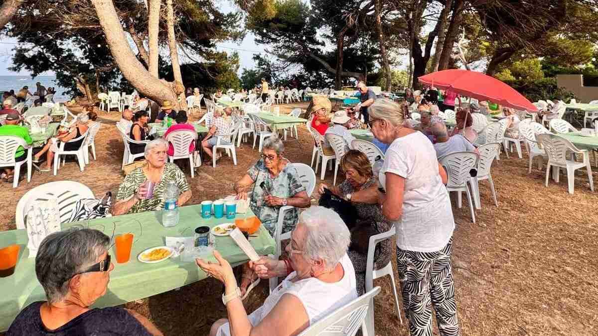 Plano general de vecinos cenando en mesas al aire libre bajo los pinos en el Port Vell