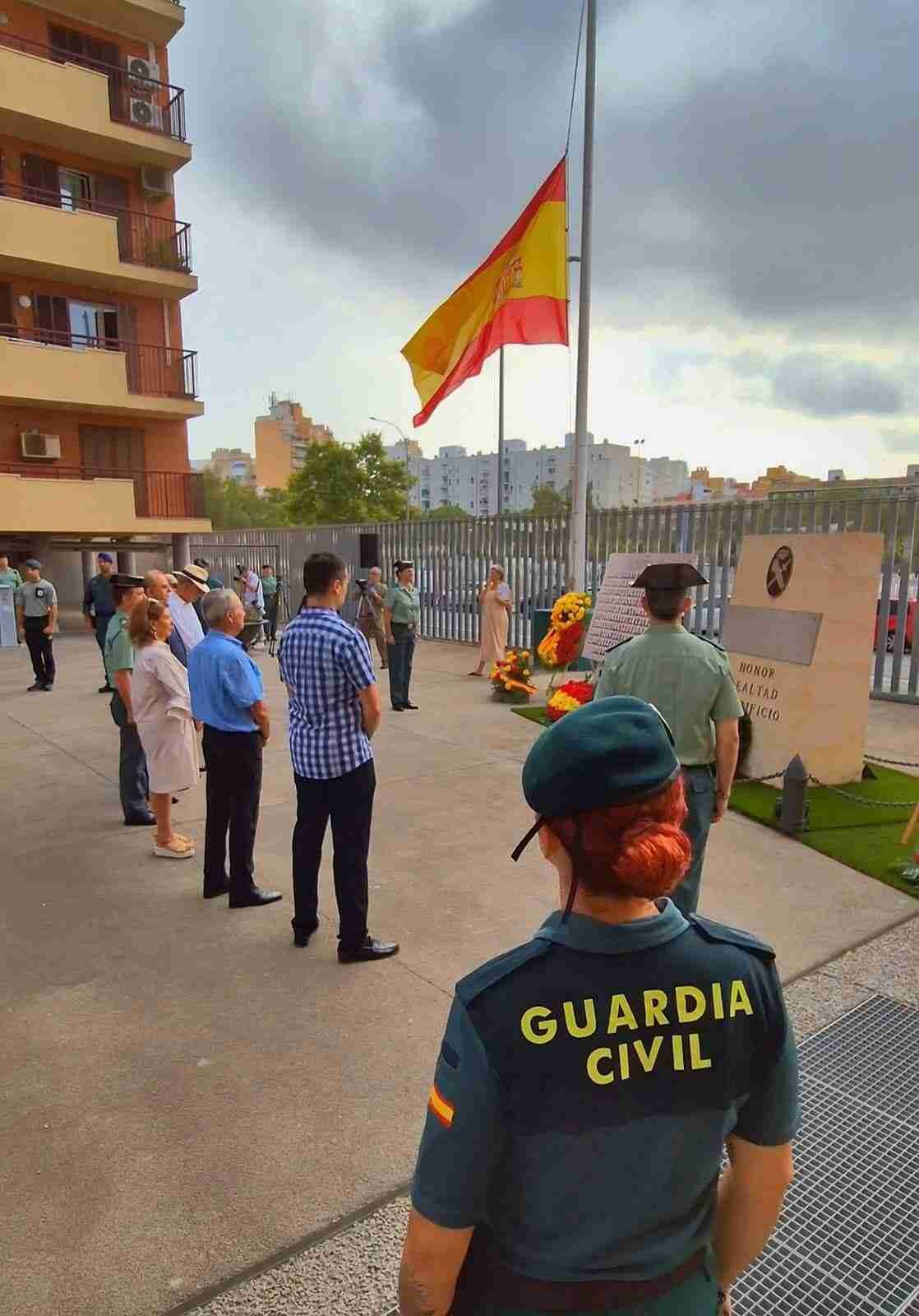 Acto solemne de la Guardia Civil frente a un monolito y la bandera de España a media asta
