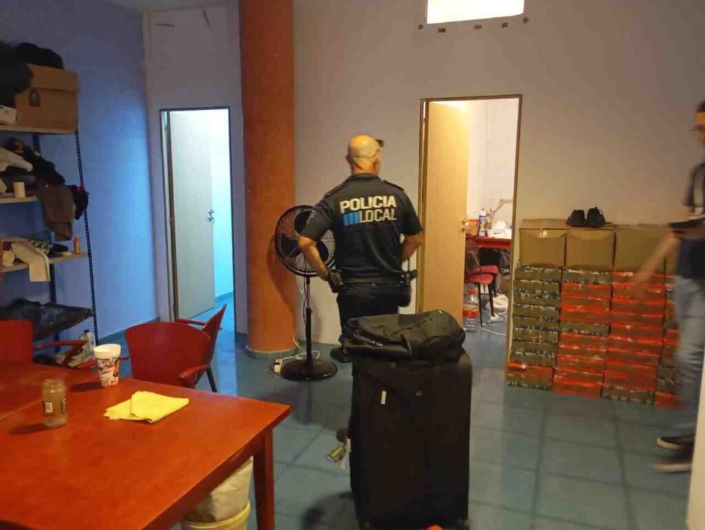 Agente de la Policía Local de espaldas en una estancia interior del restaurante entre equipajes, ventiladores y cajas apiladas