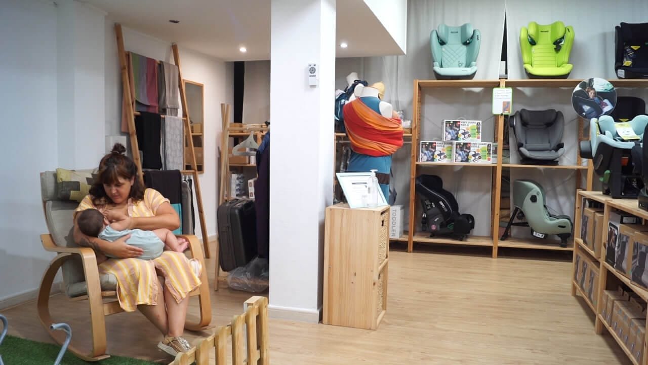 Una madre amamantando a su bebé sentada en una mecedora dentro de una tienda