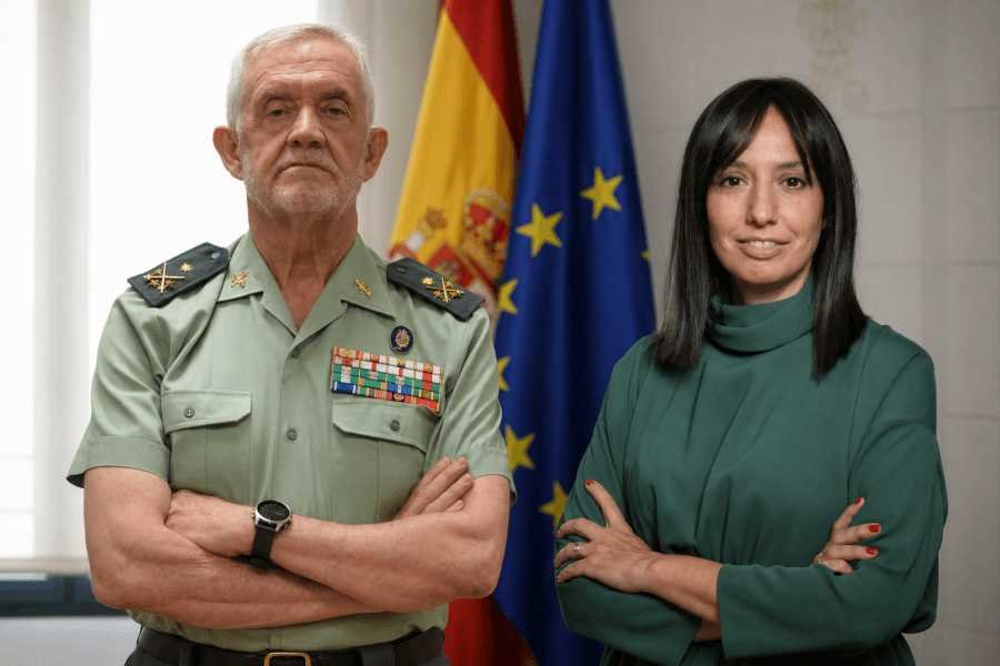 La directora general de la Guardia Civil Mercedes González y el DAO Manuel Llamas de uniforme con los brazos cruzados ante banderas oficiales