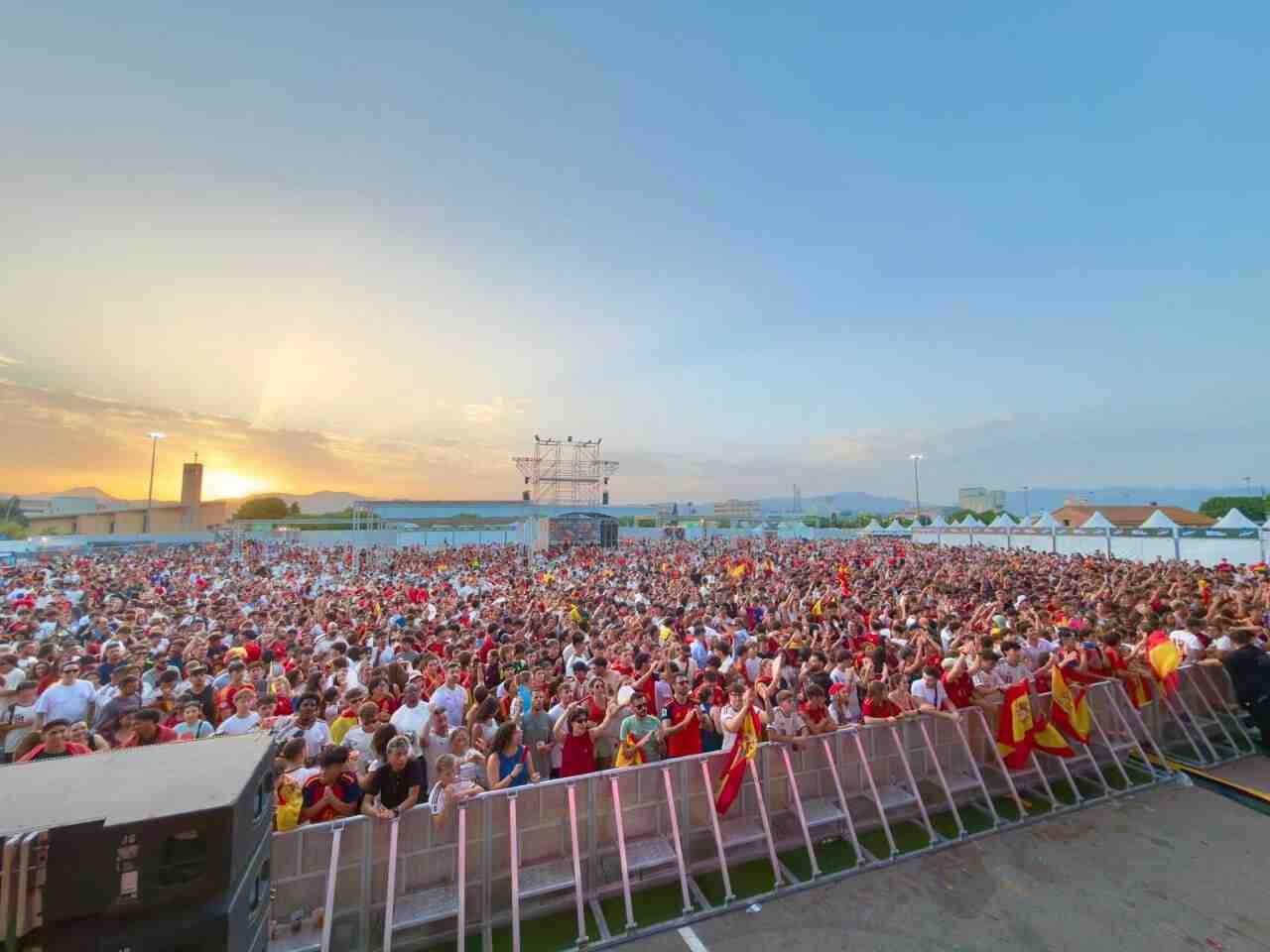 Una gran multitud de aficionados con camisetas rojas y banderas se concentra frente al escenario en Son Fusteret durante el atardecer