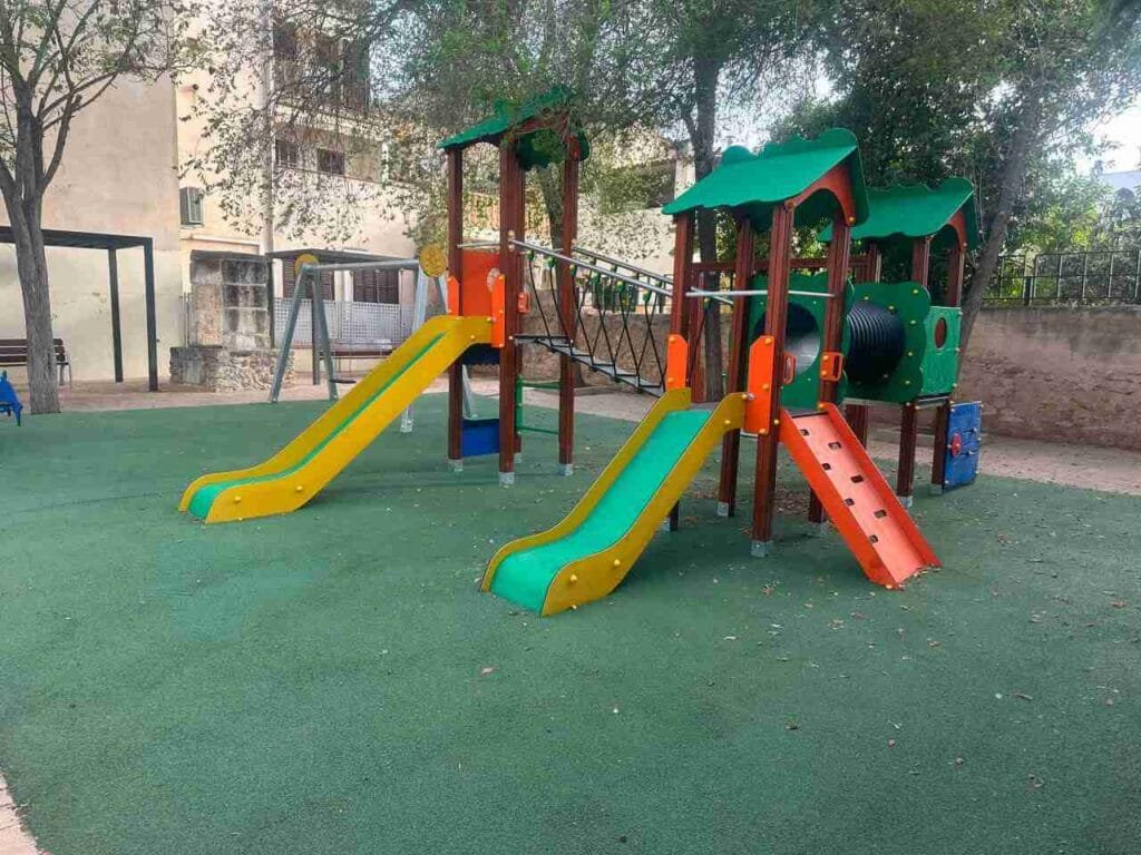 Vista lateral de la estructura central de juegos con toboganes, túnel y puente en el parque infantil de Sant Llorenç
