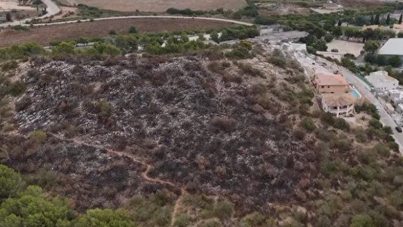 Vista aérea captada con dron que muestra la colina quemada por el incendio forestal en Son Servera, muy cerca de las casas