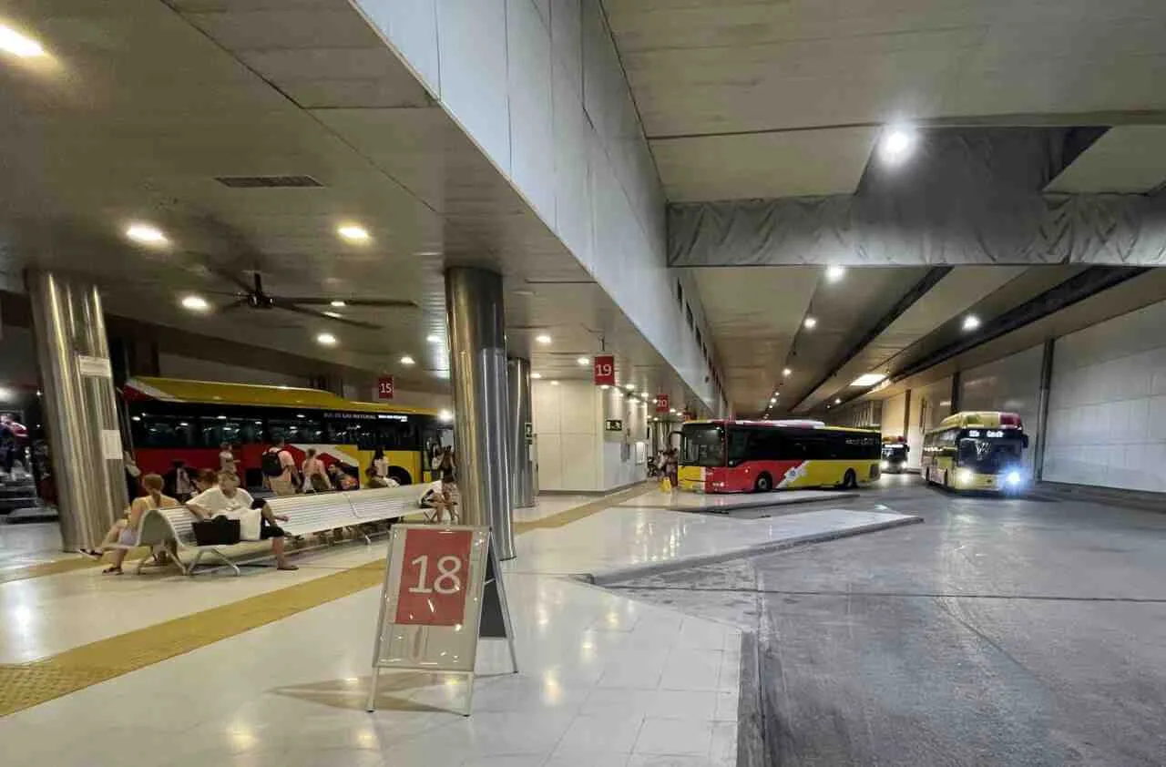 Pasajeros esperando en los bancos junto a las dársenas numeradas de autobús de la Estación Intermodal de Palma