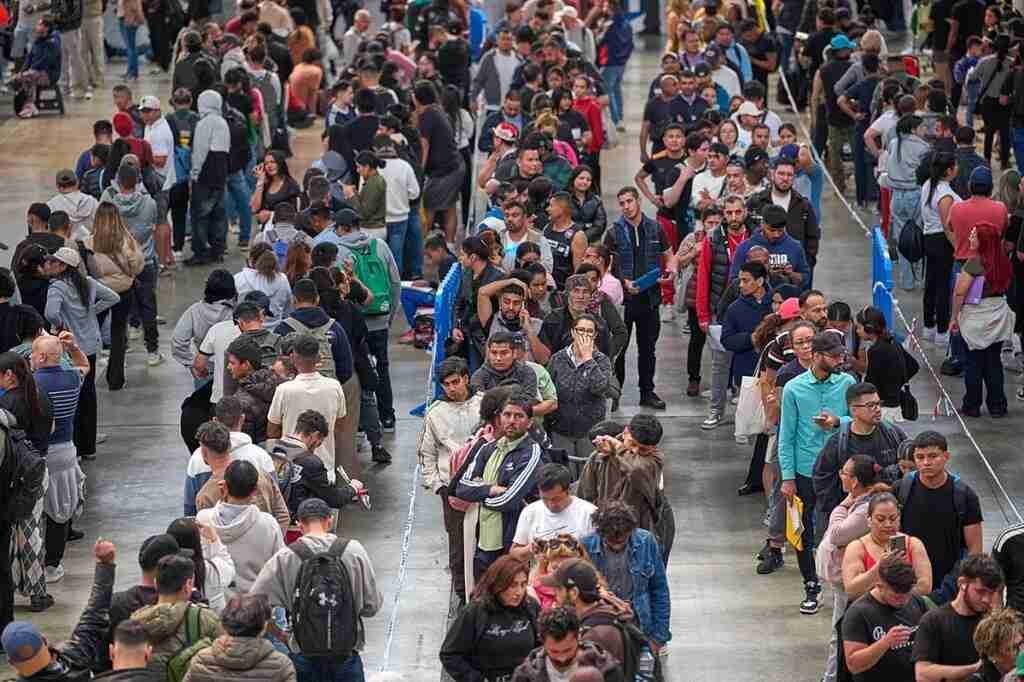 Aglomeración de personas haciendo cola en filas organizadas con vallas