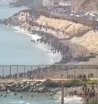 Cientos de inmigrantes ilegales bordeando la costa y la valla fronteriza en el espigón de Ceuta a pie y por mar