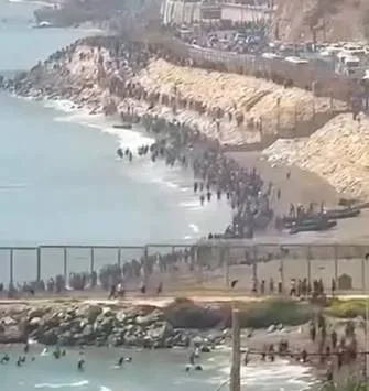 Cientos de inmigrantes ilegales bordeando la costa y la valla fronteriza en el espigón de Ceuta a pie y por mar