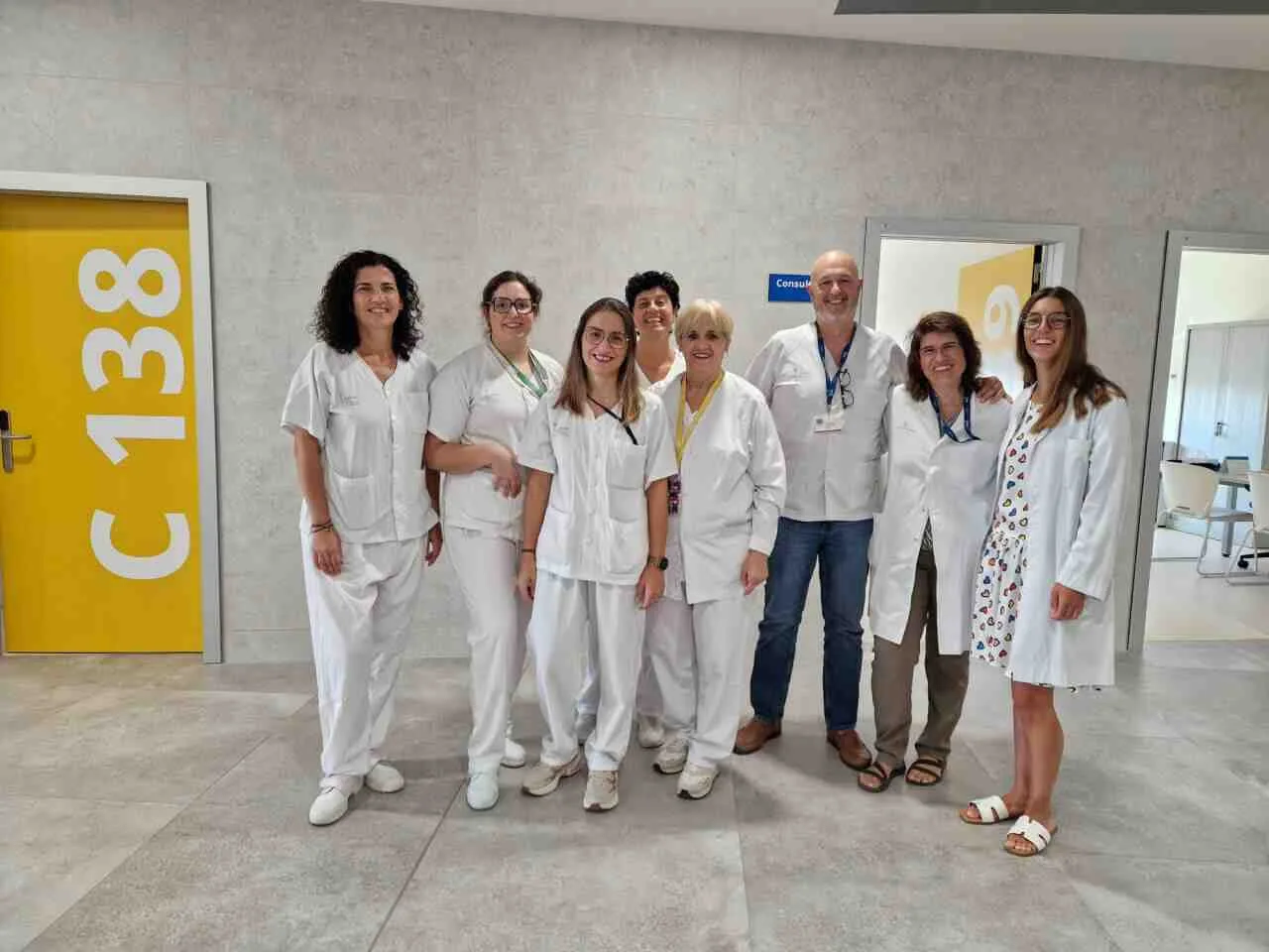 Grupo de profesionales sanitarios con batas blancas posando en el pasillo del nuevo edificio ambulatorio del Hospital de Manacor frente a las puertas de consultas
