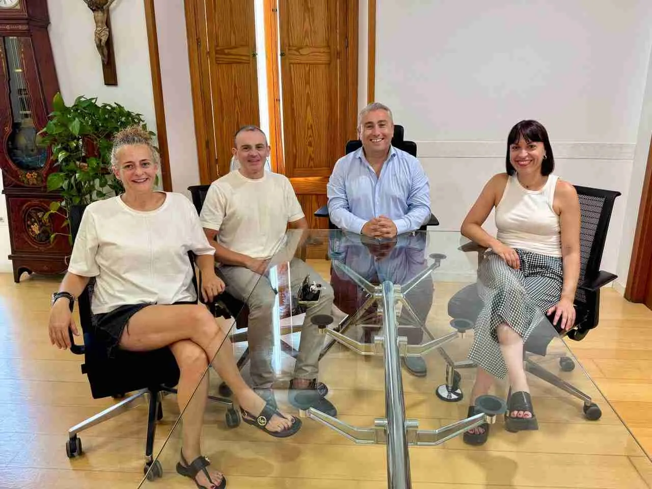 Representantes municipales y de Cáritas sentados alrededor de una mesa transparente