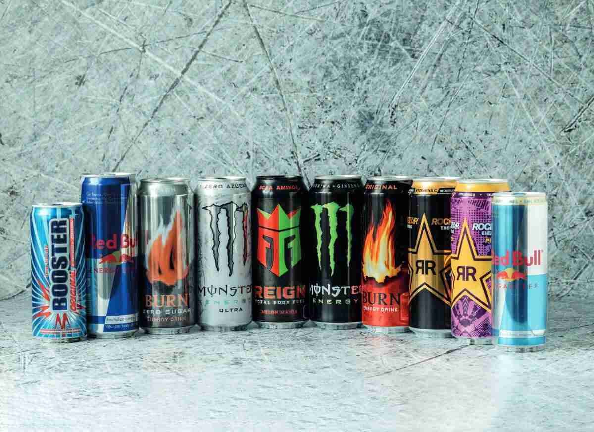 Varias latas de bebidas energéticas dispuestas en fila sobre un fondo gris