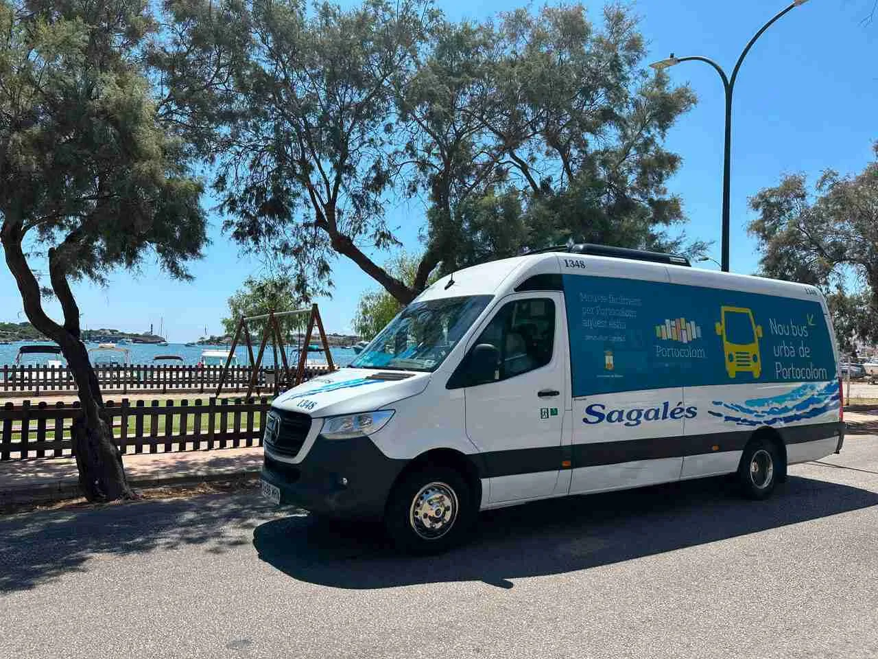 Minibús blanco de la empresa Sagalés estacionado junto al puerto de Portocolom
